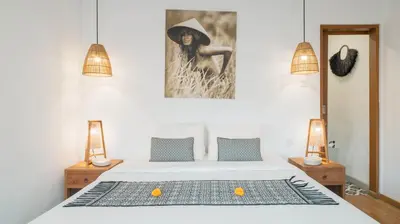 a bedroom with a bed with two lamps and a painting at Villa Umara by Villa Finder in Seminyak