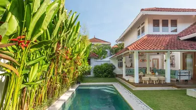 a villa with a swimming pool in front of a house at Villa Umara by Villa Finder in Seminyak