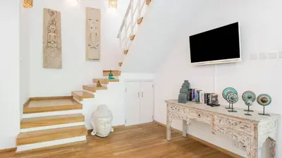 a living room with stairs and a tv on the wall at Villa Umara by Villa Finder in Seminyak