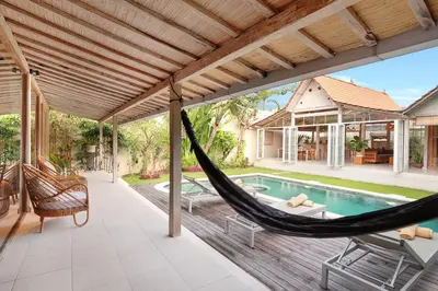 an outdoor patio with a hammock and a swimming pool at Villa Balimasan 10 mins to Canggu in Seminyak