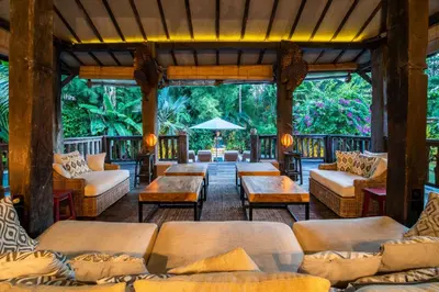 a screened in porch with couches and tables at Villa River Garden Canggu in Kerobokan