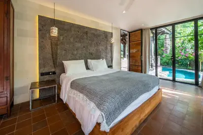 a bedroom with a large bed and a pool at Villa River Garden Canggu in Kerobokan
