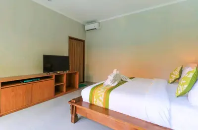 a bedroom with a bed and a flat screen tv at Three Brothers Bali Legian Bungalows & Villas in Legian