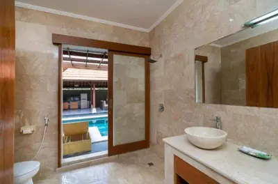 a bathroom with a sink and a mirror and a pool at Three Brothers Bali Legian Bungalows & Villas in Legian