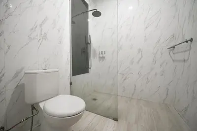 a white bathroom with a toilet and a shower at Hoki Villa by Urbanview Villa in Kerobokan