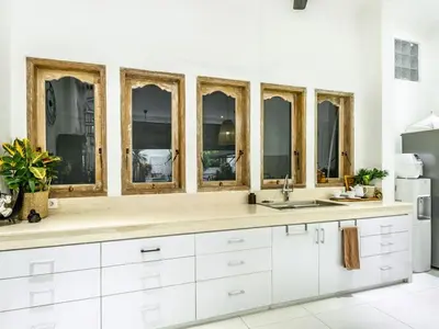 a kitchen with white cabinets and a sink and windows at Ahimsa Moon Villa Seminyak in Seminyak