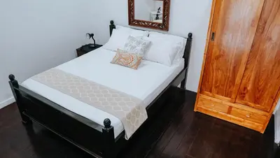 a bedroom with a bed with white sheets and a mirror at Ahimsa Moon Villa Seminyak in Seminyak