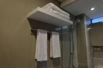a bathroom with white towels and a shower at Wirton Seminyak in Denpasar