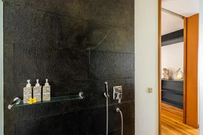 a bathroom with a black stone wall at Villa Athena in Seminyak
