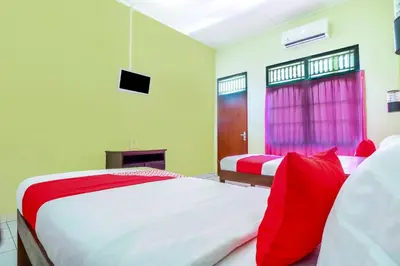 a bedroom with two beds with red and white at Hotel O Nan Berlian Inn in Legian