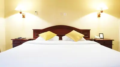 a bedroom with a large bed with two yellow pillows at Masainn Hotel Kuta in Kuta