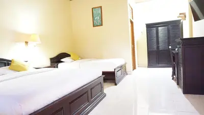 a hotel room with two beds and a door at Masainn Hotel Kuta in Kuta