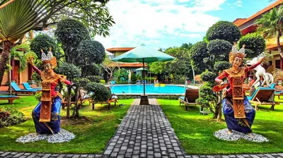 two statues in the grass next to a pool at Masainn Hotel Kuta in Kuta