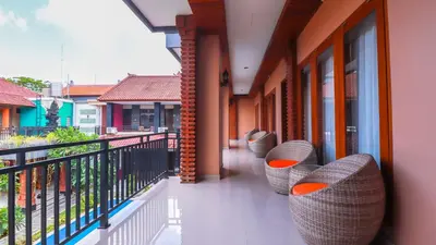 a row of chairs on the balcony of a building at Mia Guest House in Legian