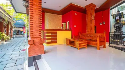 a building with red walls and benches in a street at Mia Guest House in Legian