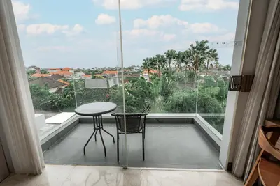 a balcony with a table and chairs and a large window at The Capital Hotel and Resort Seminyak in Seminyak