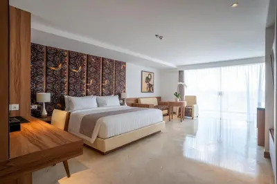 a bedroom with a large bed and a dining room at The Capital Hotel and Resort Seminyak in Seminyak