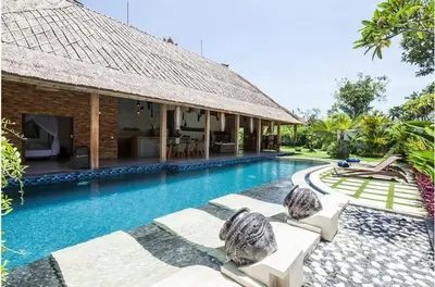 a swimming pool next to a building with a resort at Villa Katapappa in Seminyak