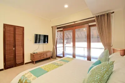 a bedroom with a large bed and a tv at UMA LIMA VILLA - 7Min Beach Access - 10min to Canggu in Canggu