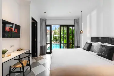 a bedroom with a bed and a desk and a pool at Villa Nago Walk to Seminyak Best Spots in Seminyak