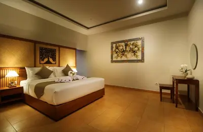 a bedroom with a large bed and a table at Sudha Villa Bali B in Seminyak