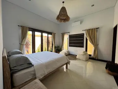 a bedroom with a large bed and large windows at Villa Margherita in Seminyak