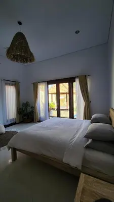 a bedroom with a large bed with a large window at Villa Margherita in Seminyak