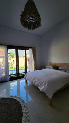 a bedroom with a large bed and a chandelier at Villa Margherita in Seminyak