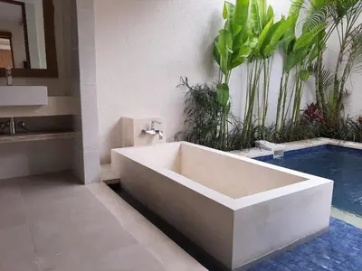 a bathroom with a bath tub next to a swimming pool at Taman Sari Pengubengan Villa in Kerobokan