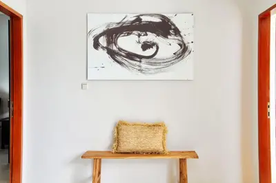 a painting hangs on a white wall above a wooden bench at Villa Maleena in Seminyak