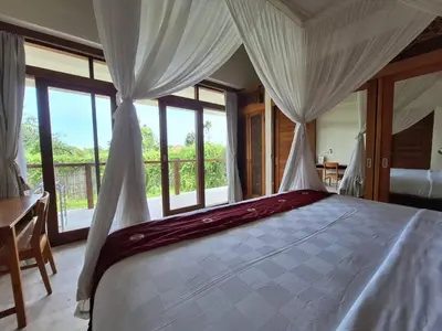 a bedroom with a bed with curtains and a window at Villa Beji in Seminyak