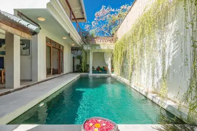 an indoor swimming pool in a house with green ivy at Villa Beji in Seminyak