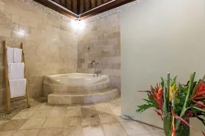 a bathroom with a tub and a vase of flowers at Casa Jimbaran Villa in Jimbaran
