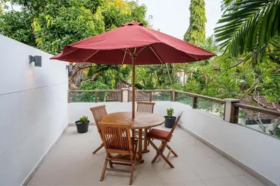 a table and chairs with an umbrella on a balcony at Villa Orange 3BR Seminyak by Exotic Bali Properties in Seminyak