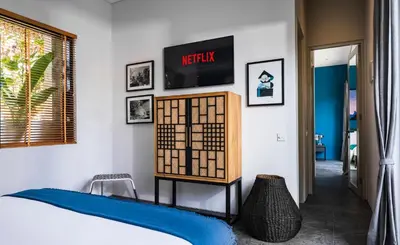 a bedroom with a bed and a tv on a wall at Summer House Villa in Canggu