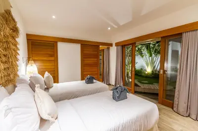 two beds in a hotel room with windows at Villa Hana by Alfred in Bali in Seminyak