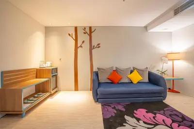 a living room with a blue couch with colorful pillows at Grand Livio Kuta Hotel in Legian