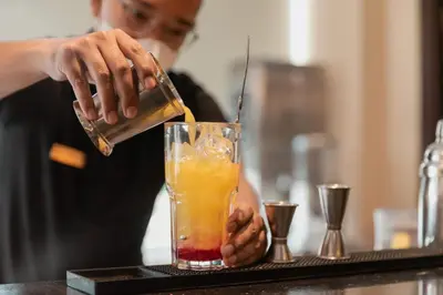 a person pouring a drink into a glass at Four Star by Trans Hotel in Sanur