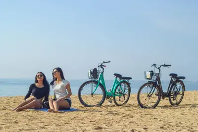 two women sitting on the beach with their bikes at Four Star by Trans Hotel in Sanur