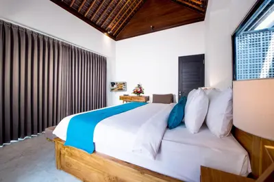 a bedroom with a large white bed with blue pillows at Villa DeDayuh Seminyak in Seminyak