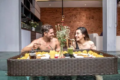 a man and woman sitting at a table eating food at Villa DeDayuh Seminyak in Seminyak