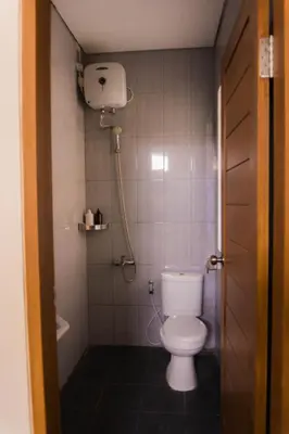 a small bathroom with a toilet and a shower at Cakra House in Denpasar