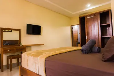 a bedroom with a bed and a desk and a television at Cakra House in Denpasar
