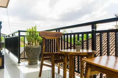 a balcony with a wooden chair and a table at Cakra House in Denpasar