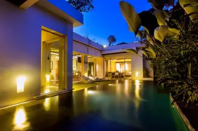 a villa with a swimming pool at night at Kedonganan Beach Villas in Jimbaran