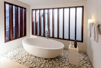 a bathroom with a white tub and large windows at Kedonganan Beach Villas in Jimbaran