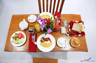 a table with plates of food and flowers on it at The Awandari Villas Seminyak in Seminyak