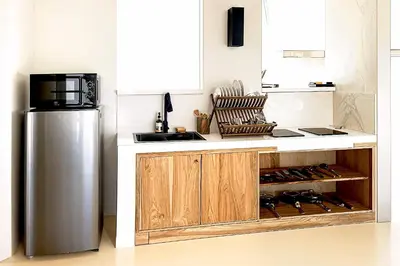 a kitchen with a stainless steel refrigerator and wooden cabinets at Villa de Malicott in Seminyak