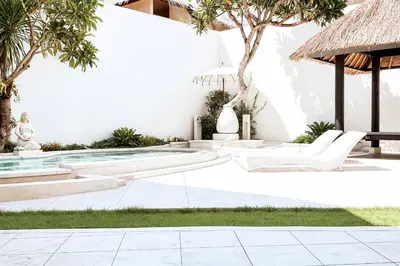 a courtyard with a pool and chairs and trees at Villa de Malicott in Seminyak