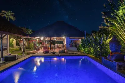a swimming pool in front of a house at night at Luxury Villa La plancha BEACH 200m, Heart of Seminyak in Seminyak